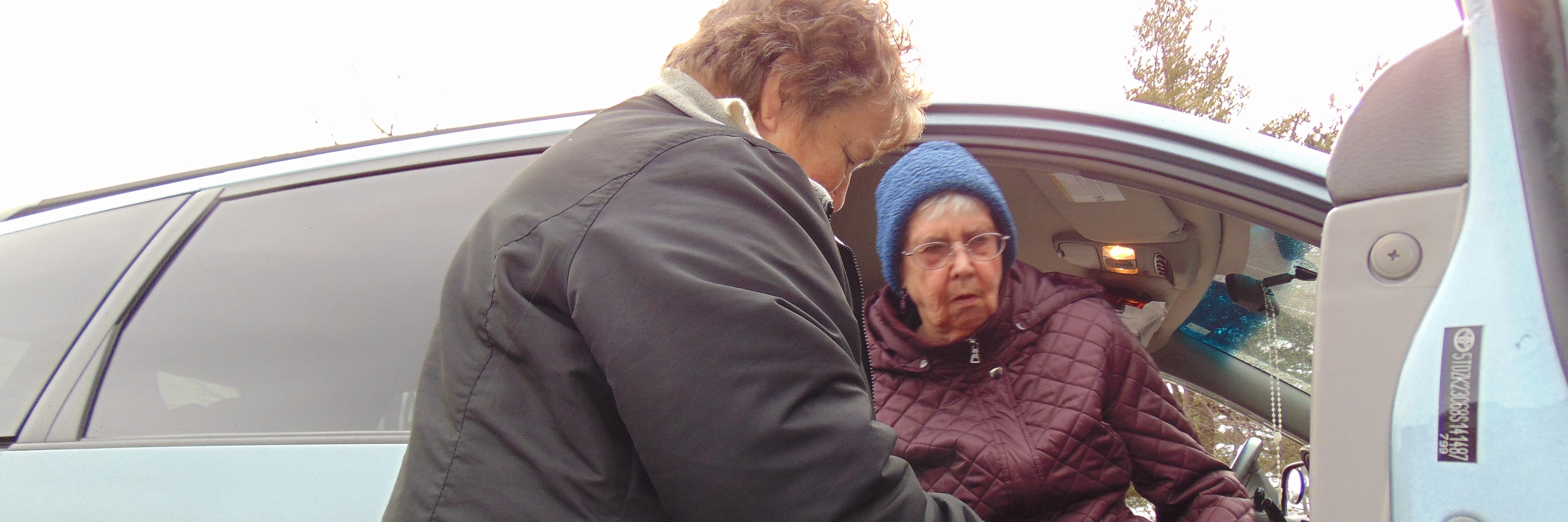 A woman helping an Older Vermonter out of a vehicle